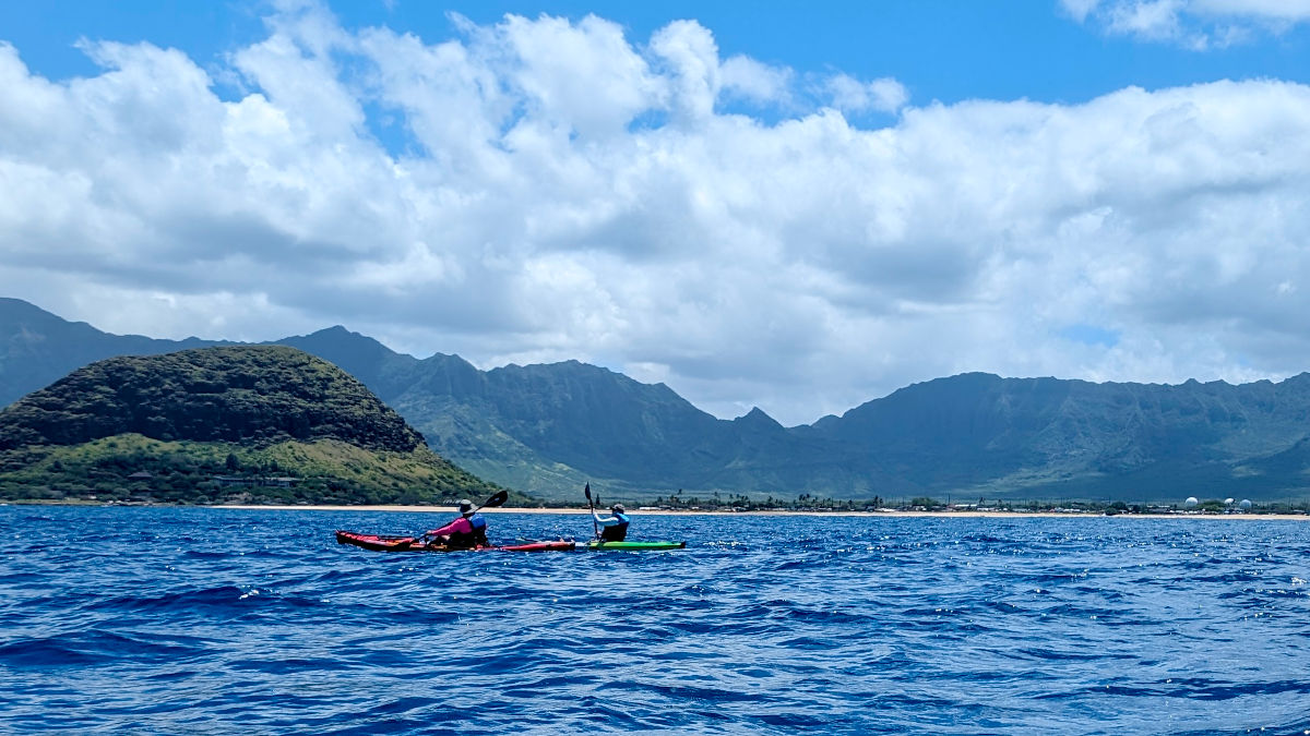 Two kayakers with the Waianae Valley in the background