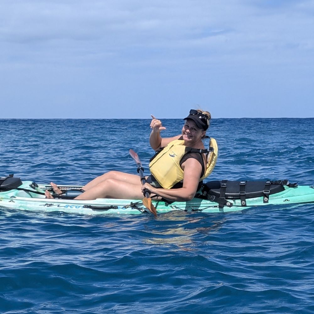 Christine flashing a shaka in a kayak