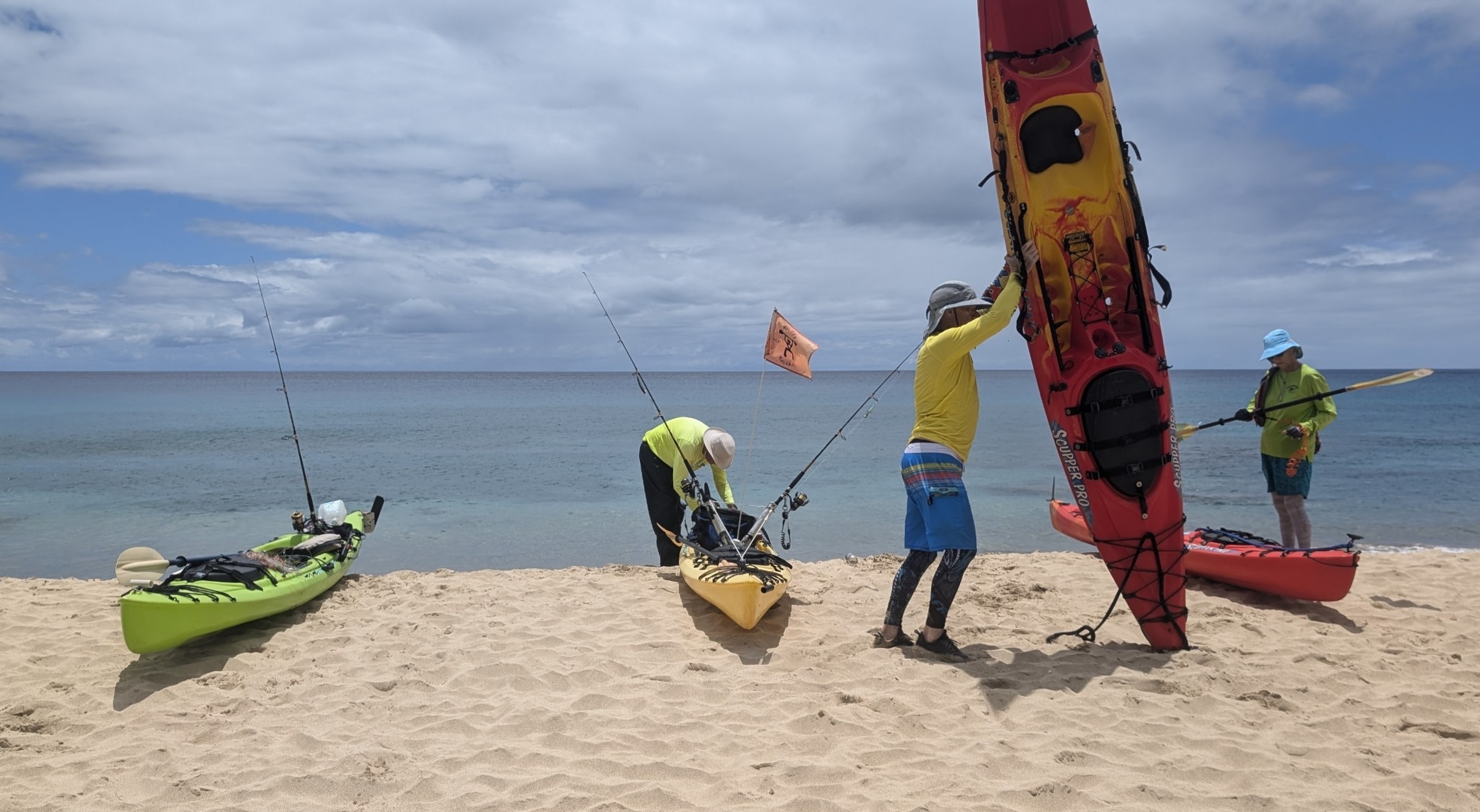 Four kayaks at Makua Beach with one kayaker standing his kayak up