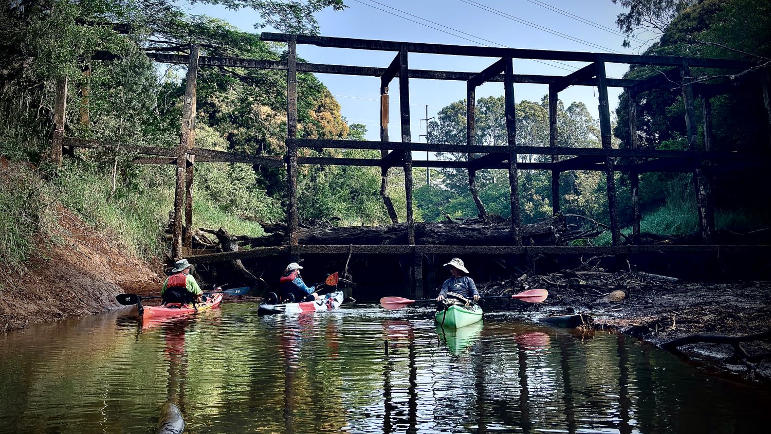 Three kayakers at an old bridge
