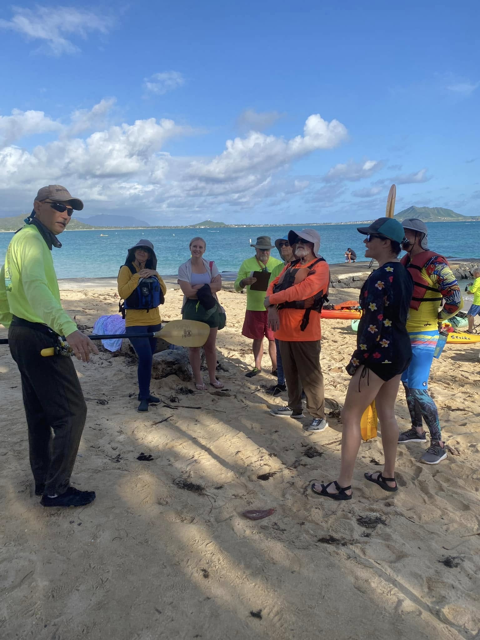 Man explains kayak surfing to others on the beach