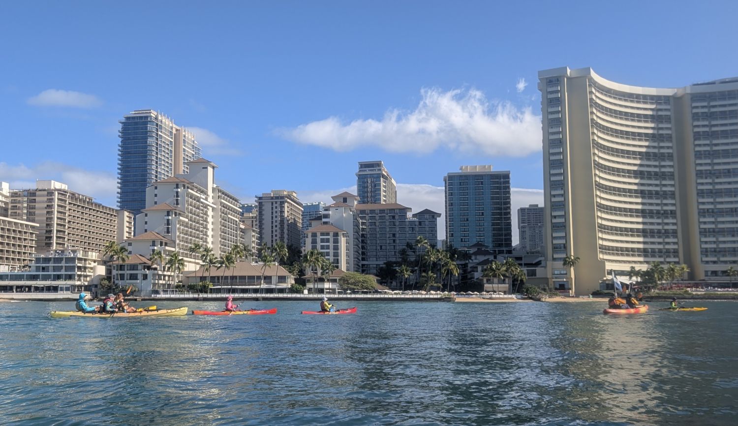 Six kayak passing the Halekulani and Sheraton hotels