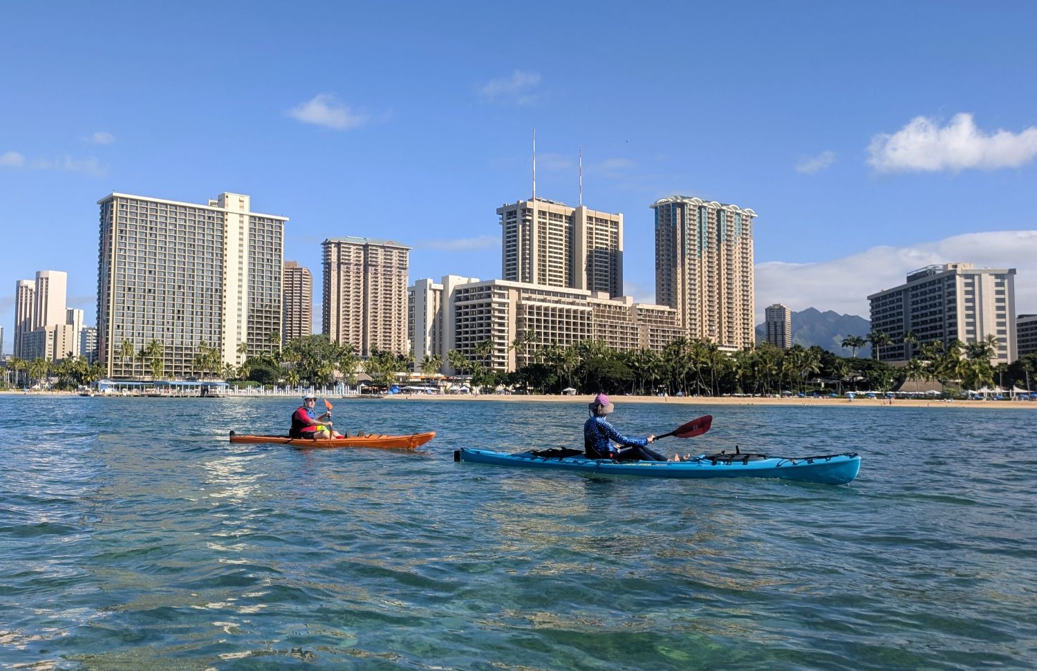 Two kayakers with the Hilton Hawaiian Village in the background