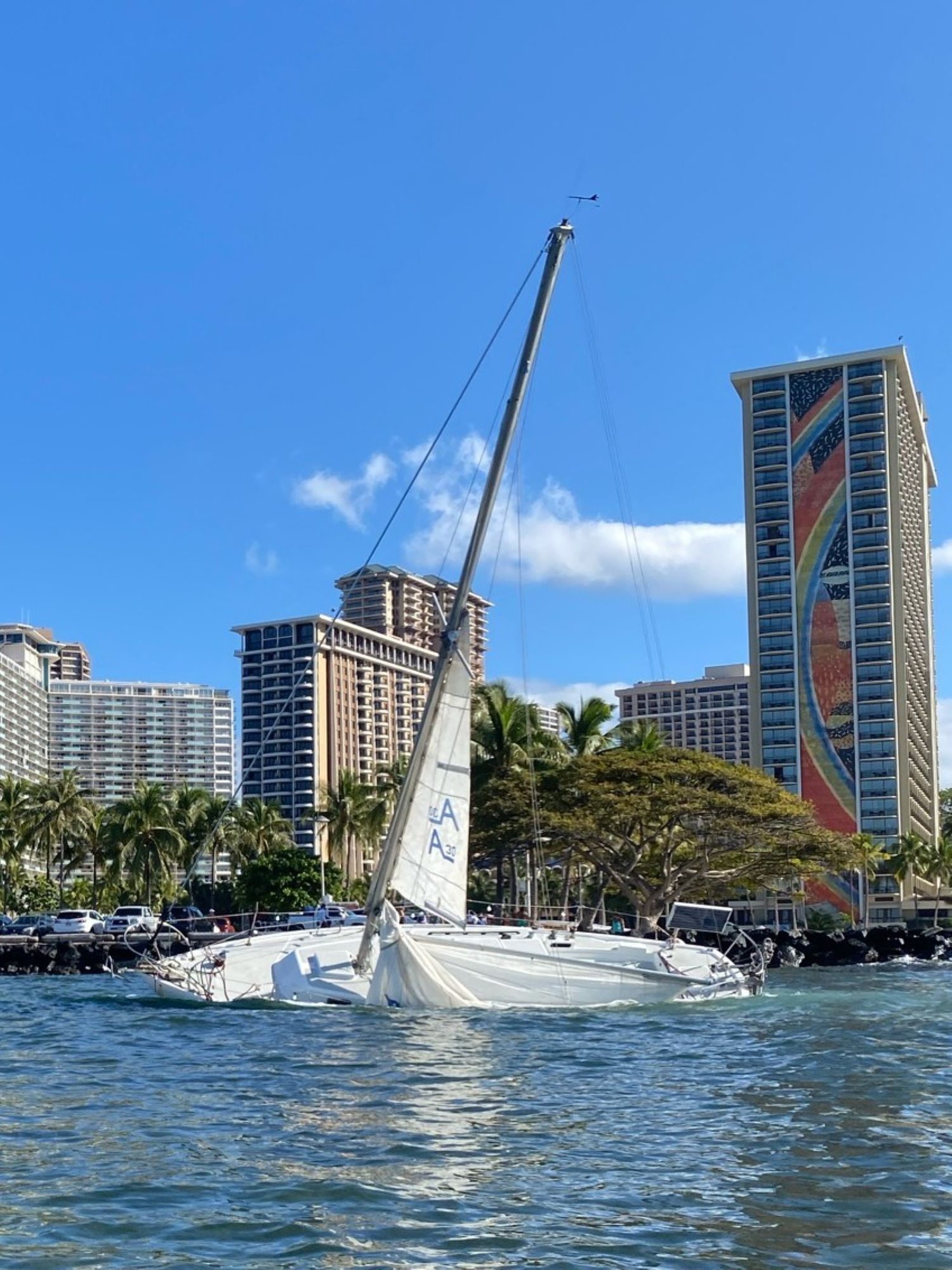 Grounded sailboat outside the Ala Wai harbor breakwater. The Hilton Rainbow Tower is in the background.