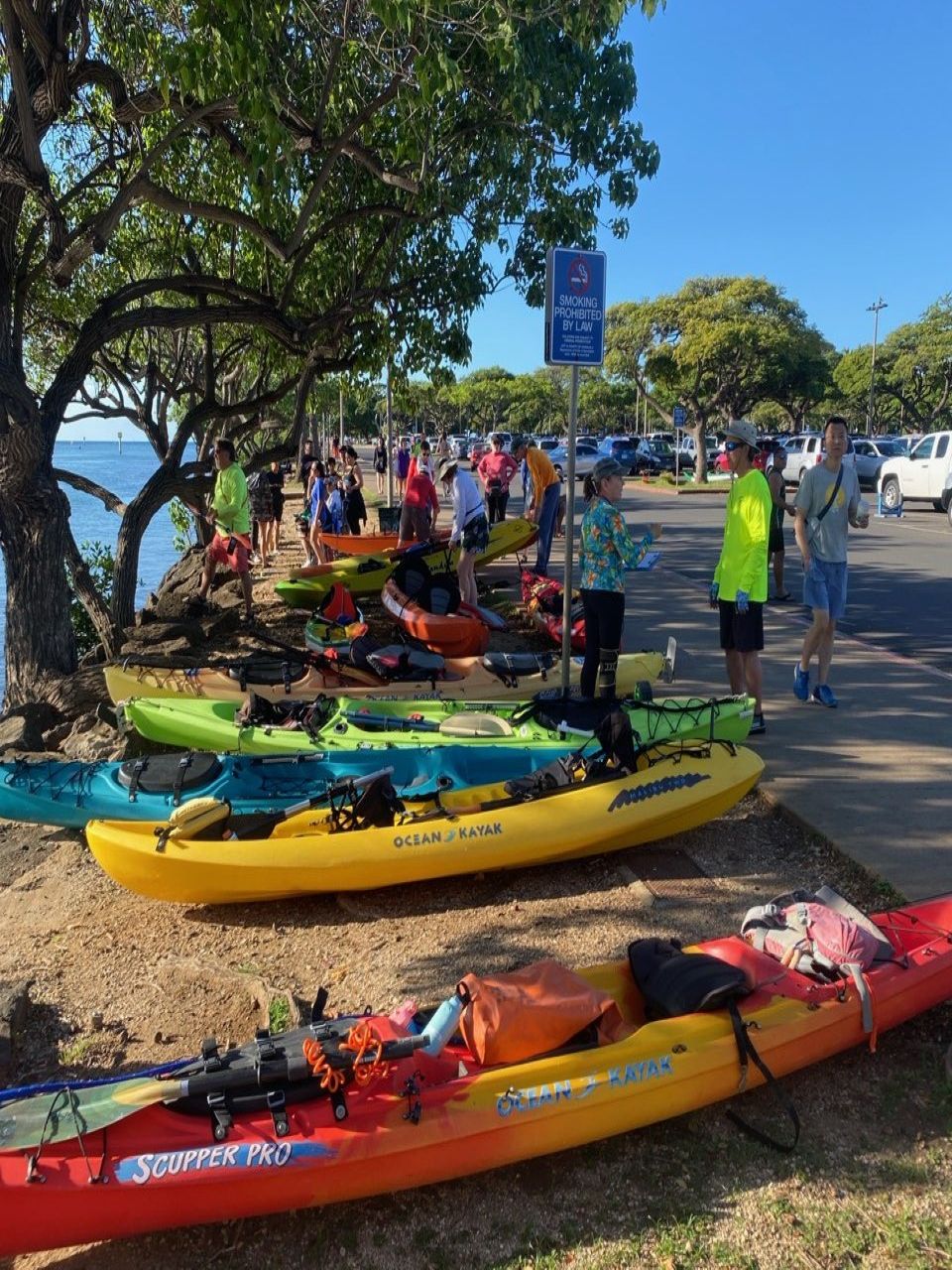 Kayaks and kayakers on the bank next to the Magic Island canoe ramp