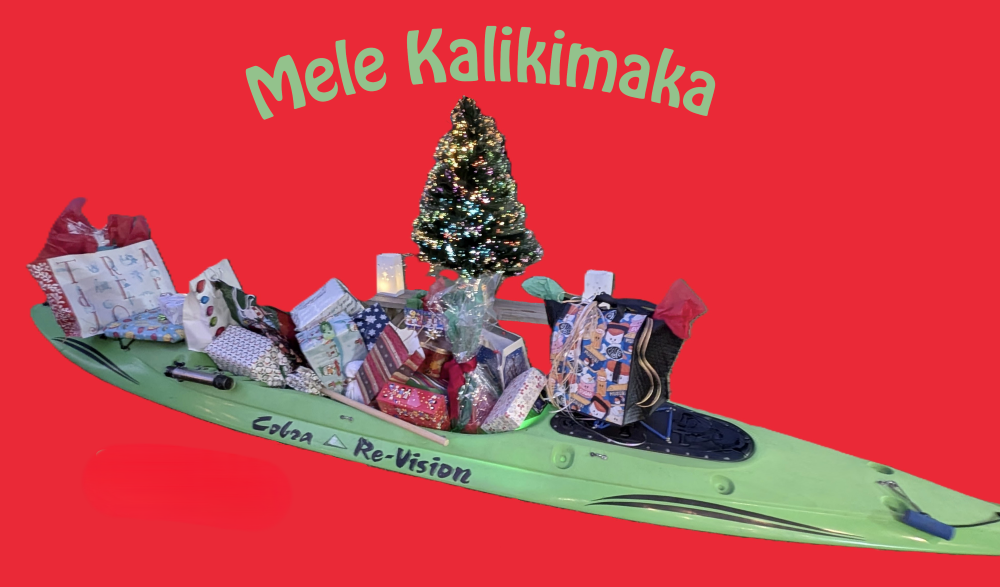 Presents on a green kayak with a lighted tree in the background