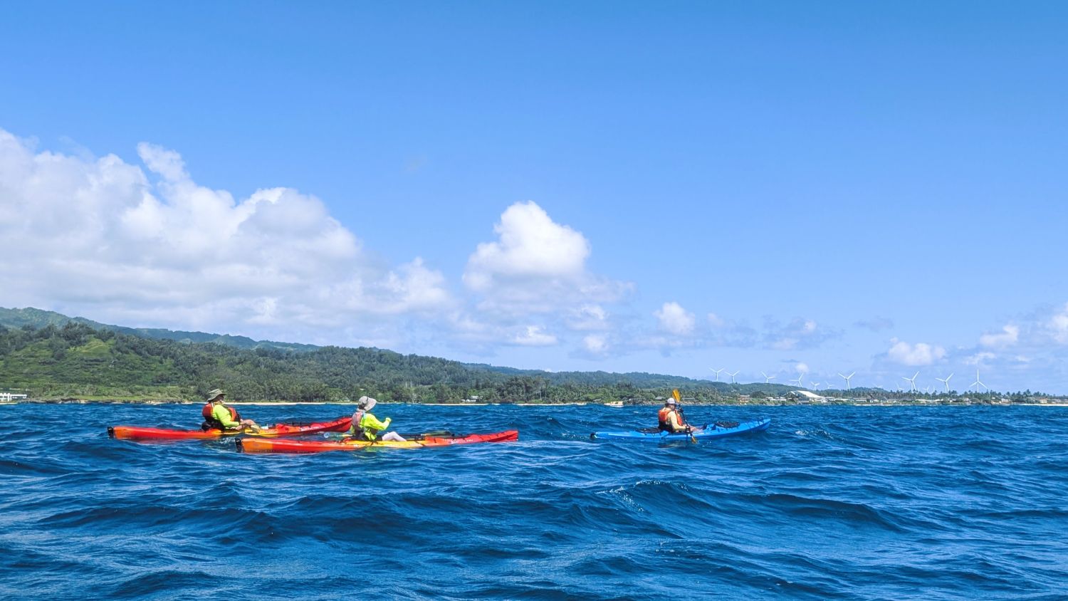 Three kayakers off of Laie with windmills in background